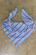 Blue Cotton Stripe Bandana with a red striped pattern, laid flat on a neutral stone background.