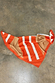 Multi Stripe Mix Bandana featuring orange, tan and white stripes and a polka dot border, displayed on a concrete floor.