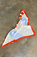 Multi Stripe Mix Bandana featuring bold orange and blue stripes and a polka dot border, draped on a grey concrete floor.
