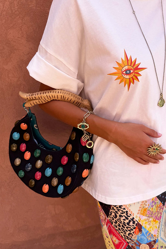Black stone beaded crescent bag with multicoloured stones and a sculpted wooden handle, worn on the arm.