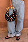 Black Stone Beaded Bag featuring multicoloured stones and a sculpted wooden handle, held against light blue denim jeans.