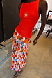 Cirque Beatrice Skirt in a multicoloured geometric print with pleats, paired with a red sun-motif tank top.