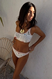 Cream Palma one-shoulder bikini top featuring hand-painted palm motifs and a contrast orange crochet trim.