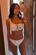 Cream Palma One Shoulder Bikini Top with hand-painted sun motifs and orange crochet trim in a mirror selfie.