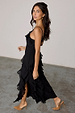 Black Molly midi dress featuring tiered ruffles, adjustable straps and a side slit on a model.