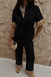 Black Raffia Marra Trousers with fringe hems, styled as a co-ord with a matching shirt and raffia clutch.