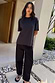 Black Studded T-Shirt in cotton with silver neckline studs and a relaxed fit, styled with black wide-leg trousers.