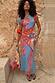 Blue Dolce Vita Mesh Dress with graphic eye and swirl motifs, styled with a matching beaded tassel bag.