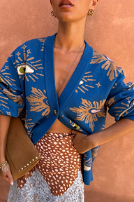 Blue Eye Cardigan in a midweight knit with iconic eye motifs, styled with a brown spotted lace-trim skirt.