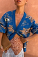 Blue Eye Cardigan in a midweight knit with iconic eye motifs, styled with a brown spotted lace-trim skirt.
