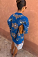 Blue Eye Cardigan with iconic eye and heart motifs, styled from behind with a white lace skirt and tan clutch.