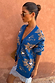Blue Eye Cardigan with gold heart and eye motifs, styled with a lace slip dress against a warm terracotta wall.