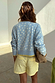 Blue Fawn Cheryl Cardigan in a pale blue deer print knit, styled with yellow striped shorts from the back.