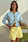 Blue Fawn Cheryl Cardigan in a soft knit with a spotted deer print and yellow trim, styled with striped shorts.