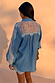 Blue Lace Marley Shirt with lace detailing on the back and sleeves, shown from a rear view against a peach wall.
