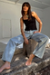 Blue Scallop Detail Straight Leg Jeans and a black vest top on a model sitting on a wooden stump.