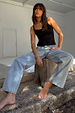 Blue Scallop Detail Straight Leg Jeans and a black vest top on a model sitting on a wooden stump.