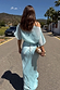 Blue Chiffon Tilly Dress with an off-the-shoulder top and satin skirt, seen from behind as a model walks outdoors.