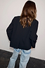 Thumbnail for Black Bow Crop Blazer back view, showing its structured silhouette and rear vent, styled with light-wash denim scallop jeans.