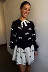 Black Bow Sophie Cardigan with cream 3D bows and a tie neck, styled with a matching bow-print mini skirt.