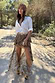 Brown Bandana Cassie Skirt with a paisley print and high-low ruffled hem, styled with a white shirt on a wooded path.