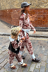 Kids Chocolate Bandana Knitted Set with a brown and blue print, worn by a child walking on a cobbled London street.