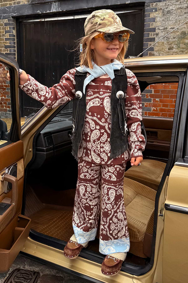 Kids Chocolate Bandana Knitted Set in a brown paisley print and blue contrast, styled with a black vest in a car doorway.