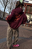 Burgundy hoodie with coral sun and snake back embroidery, styled with leopard print trousers for a street style look.