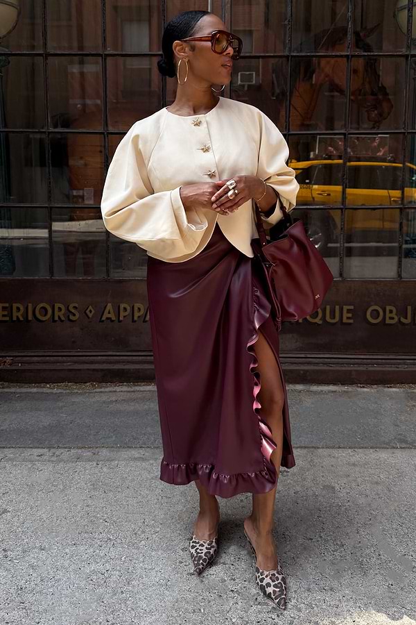 Burgundy Vegan Leather Ruffle Jaspre Skirt with side ruffles, styled with a cream jacket and leopard print heels.