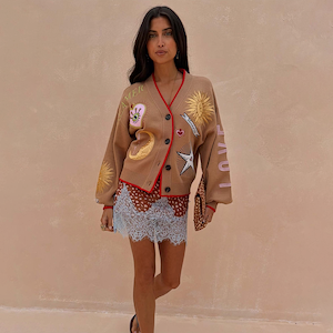 Camel Mystical Cardigan featuring sun and moon embroidery and red ribbed trim, worn by a model.