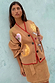 Model wears Camel Mystical Cardigan with gold sun and moon embroidery and red ribbed trim.