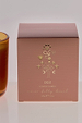 NFD Eau De Parfum Candle 002 packaging in muted pink featuring gold foil palm tree and celestial illustrations.