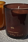 NFD Eau De Parfum Candle 001 in a burgundy glass jar with gold lettering on a sunlit stone surface.