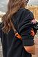 Navy Charm Bumbag with adjustable charm print strap and orange buckle, styled over a navy motif sweatshirt in London.