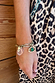 Deloris Charm Bracelet in brushed gold with eye and mermaid charms, worn with a leopard print dress.