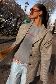 Grey tailored Check Blazer with button detailing and structured darts, styled over a grey slogan sweatshirt in an outdoor setting.