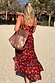 Black Cherry Sarong with a red cherry print and wrap tie waist, worn by a model on a sandy beach vacation.