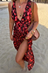 Black Cherry Sarong with a deep red cherry print and tie-waist fastening, styled on a sandy beach.
