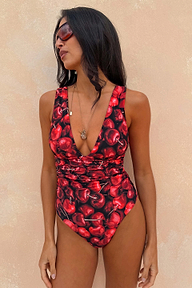 Black Cherry Plunge Suit with a deep red cherry print, plunging neckline and gathered waist detail on a model.