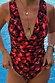 Black Cherry Plunge Suit with an all-over cherry print, plunging neckline and gathered waist, poolside.