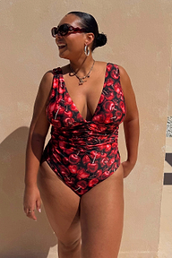 Black Cherry Plunge Suit with an all-over red cherry print, plunging neckline and gathered waist on a model.