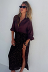 Model wearing the iconic Chocolate Sequin Jaspre Skirt with a high slit and matching brown blouse.