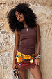 Chocolate Ribbed Tank styled with a vibrant printed mini skirt and lace trim against a stone wall.