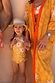 Yellow sun print swimsuit with frill details on a young girl wearing a straw hat on vacation.