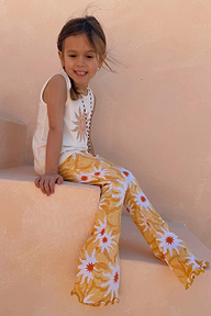 Yellow Sun Cotton Set with cream sleeveless vest and soleil print flared trousers on a girl on stone stairs.