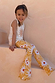 Yellow Sun Cotton Set with cream sleeveless vest and soleil print flared trousers on a girl on stone stairs.
