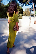 Green Shell Crochet Tilly Dress with shell embellishments and a satin skirt, shown from the back while on vacation.