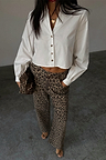 White Cropped Cotton Miley Shirt with blouson sleeves and tortoise buttons, paired with leopard print trousers.