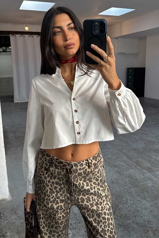 White Cropped Cotton Miley Shirt featuring tortoise buttons and blouson sleeves, paired with leopard print trousers.