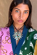 Gold Deloris Sun Necklace with semi-precious stones and a black leather cord, worn over a colourful knit cardigan.